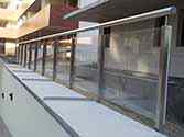 Balustrada ze stali nierdzewnej polerowanej z wypełnieniem ze szkła bezpiecznego zespolonego wzdłuż zjazdu do garażu podziemnego