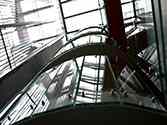 Eliptyczna powierzchnia wypełnienia balustrady całoszklanej na klatce schodowej. Mocowanym szkła do spocznika za pomocą uchwytów punktowych